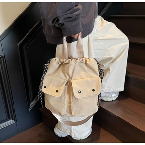 Detailed view of beige canvas bucket bag with multi-pocket design and drawstring closure