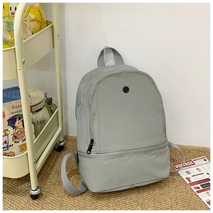 Close-up of light grey waterproof nylon backpack with front pocket and round logo