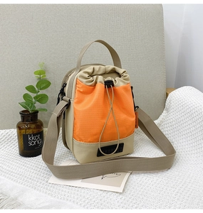 Détail d'un mini sac seau d'extérieur en nylon avec poche orange sur une couverture douce