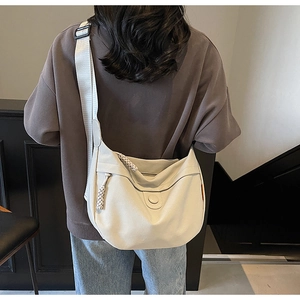 Detail view of large canvas crescent bag showing textured fabric and wide shoulder strap