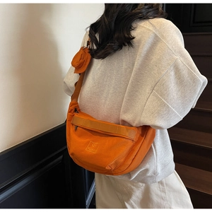Détail du sac bandoulière orange en nylon avec mini porte-monnaie rond amovible sur la sangle