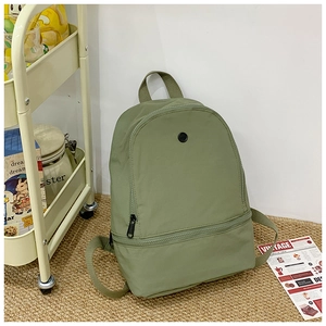 Detail view of the green nylon kids backpack with adjustable straps and round logo