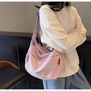 Detail of light purple canvas hobo bag showing woven zipper pull and orange brand label