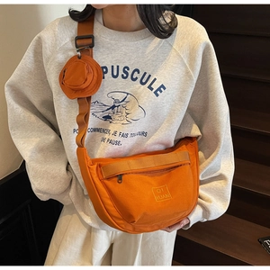 Détail du sac hobo en toile orange avec petite pochette ronde et fermeture éclair