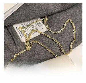 Gros plan sur la chaîne dorée brillante et les coutures de ce mini sac à bandoulière crème