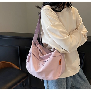 Detail of taro purple canvas shoulder bag featuring a wide strap and brand side label