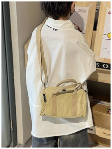 Detail of light khaki nylon cylinder crossbody bag shown on model with adjustable strap