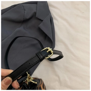 Detail of the black leather shoulder strap with gold buckle on leopard print bucket bag