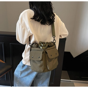 Detailed view of the olive nylon bucket bag with dual front pockets and wide strap
