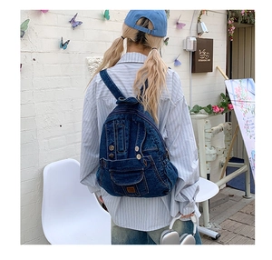 Outdoor shot of a blue denim backpack with vintage pocket details on a female model