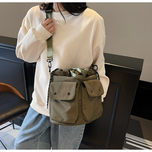 Olive green canvas bucket bag detail with dual functional front pockets and drawstring close
