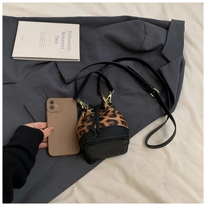 Mini leopard print bucket bag size comparison with smartphone on grey blazer
