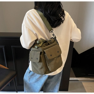 Rear view of model wearing army green canvas drawstring bucket bag with multiple pockets