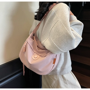 Close-up of pink canvas dumpling bag worn by model, showing side label and pocket detail