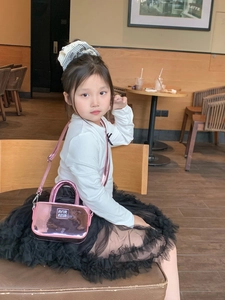 Mini borsa rosa a specchio per bambine indossata da una modella bambina in un caffè
