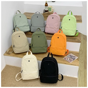 Collection of minimalist kids backpacks in nine colors displayed on wooden steps