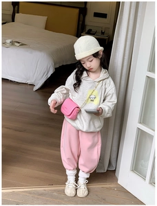 Détail d'une fillette en sweat à capuche blanc et pantalon rose avec un mini sac rose