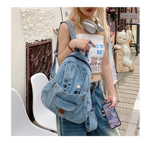 Street style view of a vintage washed denim backpack with multiple pockets and metal buckles