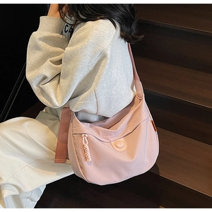 Detail of light pink canvas hobo bag with adjustable strap and decorative side label