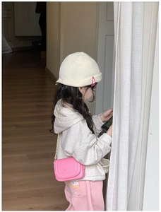 Petit sac rose à bandoulière chaîne dorée porté avec une tenue d'hiver pour enfant