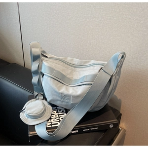 Détail d'un sac bandoulière bleu clair en nylon avec un mini porte-monnaie rond