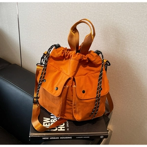 Detailed view of orange nylon drawstring bucket bag with dual front flap magnetic pockets