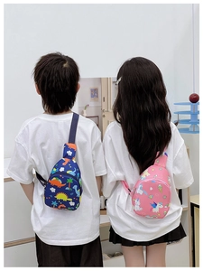 Children's navy dinosaur and pink unicorn chest bags worn by kids in a cozy home setting