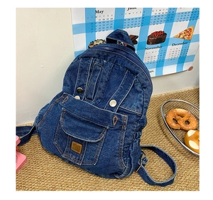 Detail of dark blue denim backpack with metal buckle pockets and vintage utility stitching