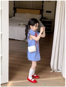 Détail de robe vichy bleue pour fille avec ruban rouge et sac bandoulière blanc