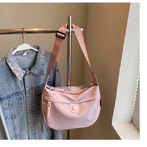 Detail of light pink canvas crescent bag with wide strap and woven zipper pull
