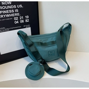 Détail du sac croissant en toile vert foncé avec patch et petit porte-monnaie rond