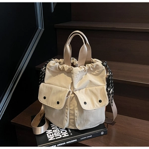 Detail of off-white canvas drawstring bucket bag with dual front pockets on wooden steps