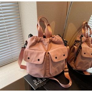 Detail of pink nylon bucket bag with drawstring closure and two front cargo pockets