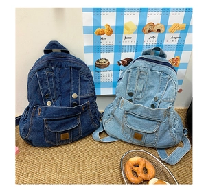 Detail view of washed denim backpacks in light and dark blue with creative face-like pockets