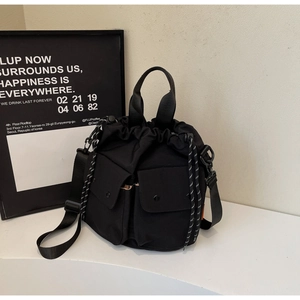 Detail of black nylon drawstring bucket bag with utility pockets and woven drawcord