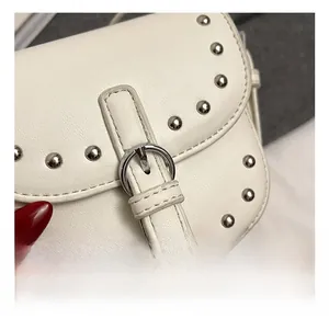 Detail showing white leather saddle bag with silver studs and polished metal buckle hardware