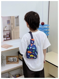 Child wearing a navy blue chest bag with colorful dinosaur prints and adjustable strap