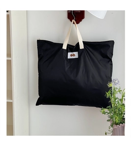 Detail of a large black nursery storage bag with cartoon patch and white handles