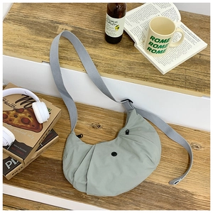 Detail der hellgrünen Halbmond-Nylontasche mit verstellbarem Gurt auf Holzstufe