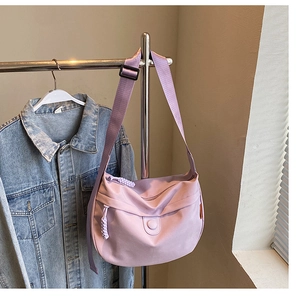 Detail view of lavender canvas dumpling bag with adjustable strap and braided zipper pull