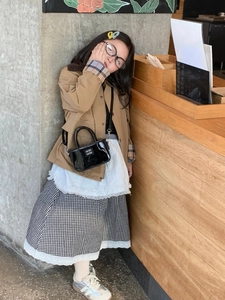 Mini borsa a mano in vernice nera con logo AMR portata da una bambina con outfit alla moda
