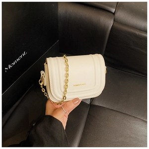 Détail du sac à bandoulière matelassé blanc avec chaîne dorée et lettrage embossé