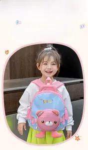 Détail du sac à dos rose et bleu avec ours 3D porté par une petite fille souriante