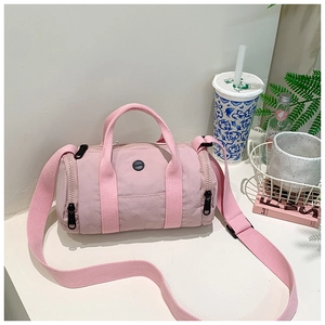 Detailed view of pink cylindrical kids' crossbody bag with black zipper and logo