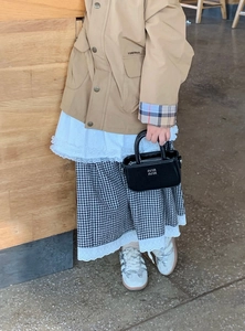 Dettaglio della borsa a mano in pelle nera per bambina e outfit alla moda