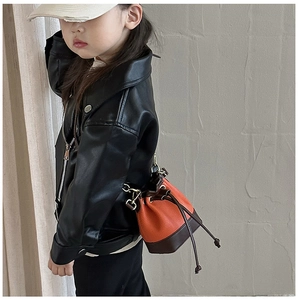 Detail of kids drawstring bucket bag in orange litchi leather with gold hardware