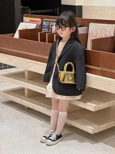 Dettaglio di una mini borsa dorata effetto specchio con trama a rilievo per bambini