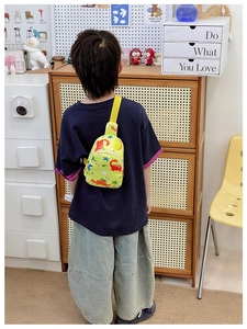 Detail of cute dinosaur print on yellow kids crossbody chest bag with adjustable strap