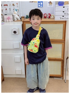 Close-up of yellow kids crossbody bag with colorful dinosaur prints on a young boy