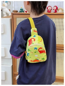 Detail view of children's yellow crossbody chest bag with colorful cartoon dinosaur prints